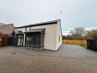 a white building with black windows and a fence at Rose Cottage by Sasco in Blackpool