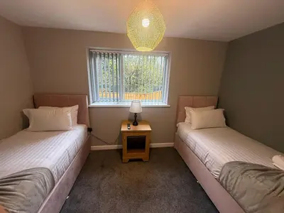 two twin beds in a room with a window at Rose Cottage by Sasco in Blackpool