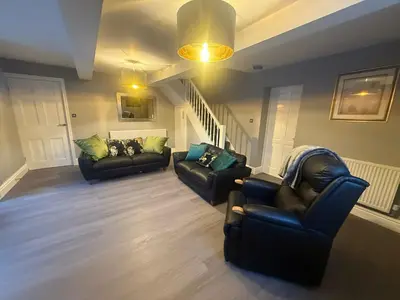 a living room with two couches and a staircase at Rose Cottage by Sasco in Blackpool