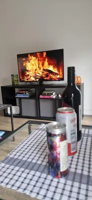 a table with a bottle of wine and a fire in a living room at Sarah's Woodland Liverpool Stays in Waterloo
