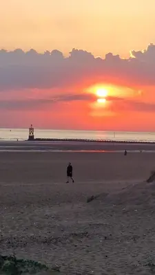 a person walking on the beach at sunset at Sarah's Woodland Liverpool Stays in Waterloo