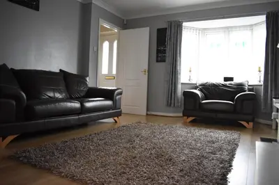 a living room with two black leather couches and a rug at Liverpool Redwood house in Liverpool