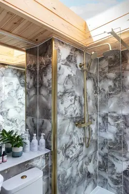 a shower in a bathroom with a marble wall at Hidden Hills Luxury Glamping in Arkholme