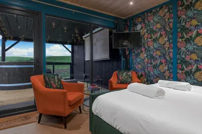 a hotel room with a bed and two chairs at Hidden Hills Luxury Glamping in Arkholme