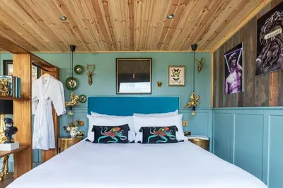 a bedroom with a bed with a blue wall at Hidden Hills Luxury Glamping in Arkholme