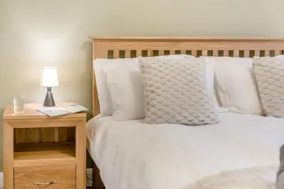 a bed with white pillows and a table with a lamp at 3 Bed in Baycliff oc-b34152 in Baycliff