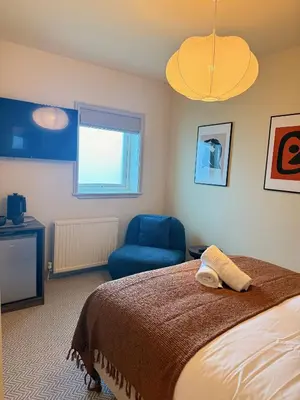 a bedroom with a bed and a blue chair at The Meridian in Southport