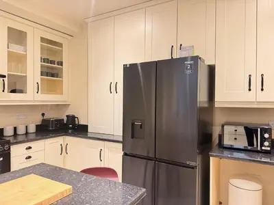 a kitchen with a stainless steel refrigerator and white cabinets at The Meridian in Southport