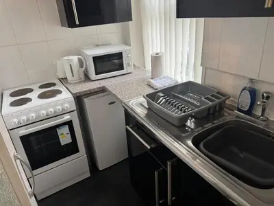 a kitchen with a sink and a stove and a microwave at 1BR Apartment in Blackpool l Sleeps 4, Fully Furnished in Blackpool