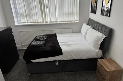 a bed with a black frame in a bedroom at 1BR in Blackpool l Sleeps 4, Wi-Fi & Full Kitchen in Blackpool