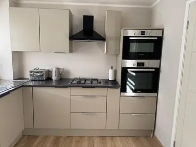 a kitchen with white cabinets and a stove top oven at Livs cozy corner in Crossens