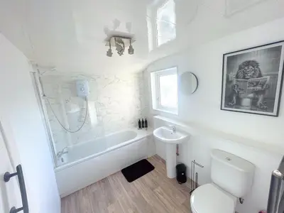 a white bathroom with a tub and a toilet and a sink at Three Bedroom House by Brookland Stays Serviced Accommodation & Short Lets in Preston with Free WiFi in Preston