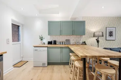 a kitchen with green cabinets and a wooden table at Earle House - Air Host & Stay - 5 BR - Sleeps 13 in Liverpool