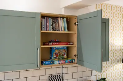 a kitchen cupboard with books and games in it at Earle House - Air Host & Stay - 5 BR - Sleeps 13 in Liverpool