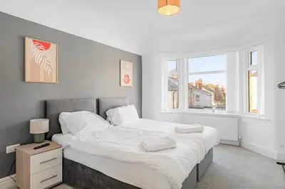 a bedroom with a large bed with white sheets at 7-Bed Contractor House in Wallasey- free parking in Wallasey