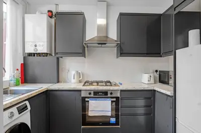 a kitchen with black cabinets and a stove top oven at 7-Bed Contractor House in Wallasey- free parking in Wallasey