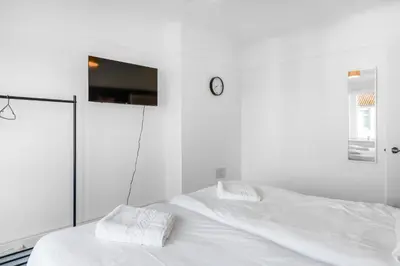 a white bed with two white pillows and a clock at 7-Bed Contractor House in Wallasey- free parking in Wallasey