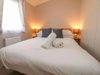 a bedroom with a white bed with towels on it at Poppy Lodge in Morecambe