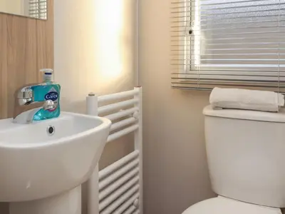 a white bathroom with a sink and a toilet at Poppy Lodge in Morecambe