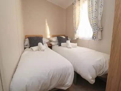 two twin beds in a room with a window at Poppy Lodge in Morecambe