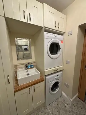 a small bathroom with a sink and a washing machine at Morton suite in Litherland