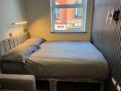 a bed in the corner of a room with a window at The Stadium Hotel Anfield in Liverpool