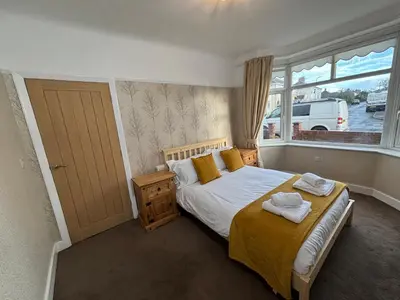 a bedroom with a bed with yellow sheets and a window at Henry suite in Litherland