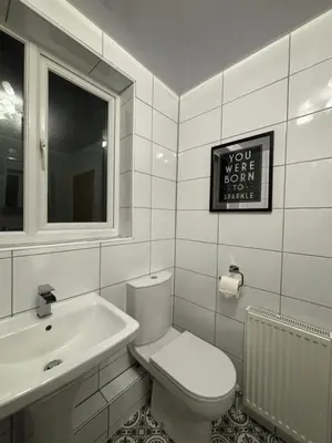 a white bathroom with a toilet and a sink at Henry suite in Litherland