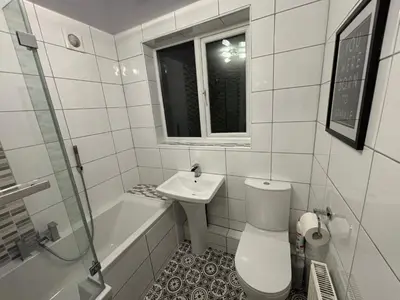a white bathroom with a toilet and a sink at Henry suite in Litherland