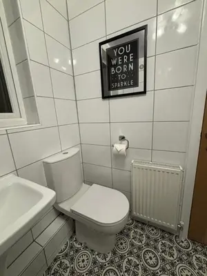 a white bathroom with a toilet and a sink at Henry suite in Litherland