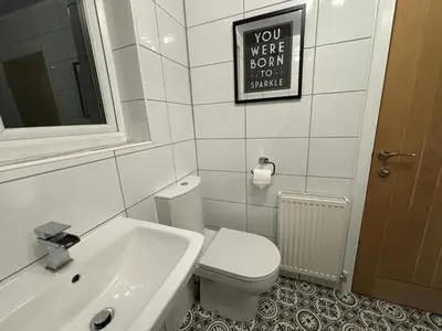 a bathroom with a toilet and a sink and a sign at Henry suite in Litherland