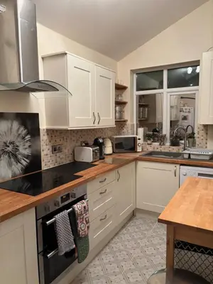 a kitchen with white cabinets and a stove top oven at Thirlmere Stay in Litherland