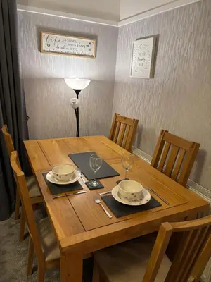 a wooden table with plates and wine glasses on it at Thirlmere Stay in Litherland