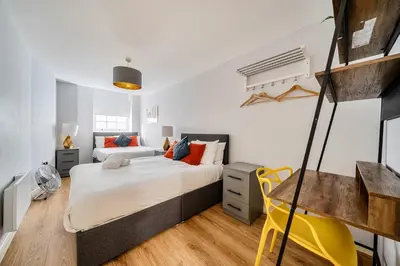 a bedroom with a bed and a yellow chair at Host & Stay - Stanley Street Apartments in Liverpool