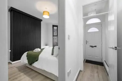 a bedroom with a white bed and a black and white door at Bibbys in Litherland