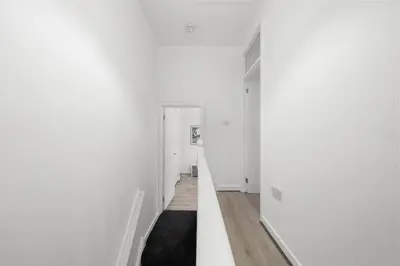 a hallway with white walls and wood floors at Bibbys in Litherland