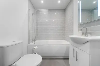 a white bathroom with a tub and a toilet and a sink at Bibbys in Litherland