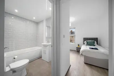 a white bathroom with a bed and a bath tub at Bibbys in Litherland