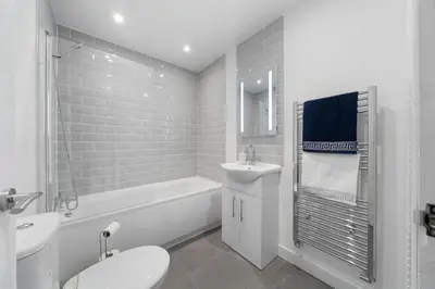 a white bathroom with a toilet and a sink at Bibbys in Litherland