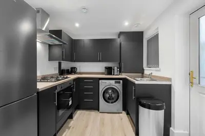 a kitchen with black cabinets and a washing machine at Bibbys in Litherland
