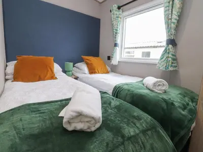 two beds with towels on them in a room with a window at The Retreat in Morecambe