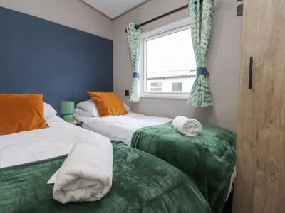 two beds in a room with a window and towels at The Retreat in Morecambe