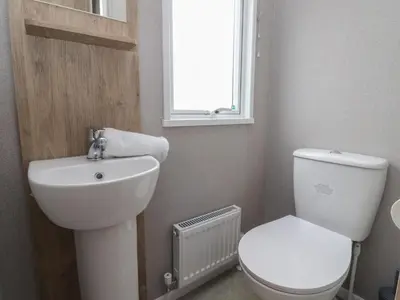 a bathroom with a toilet and a sink and a window at The Retreat in Morecambe