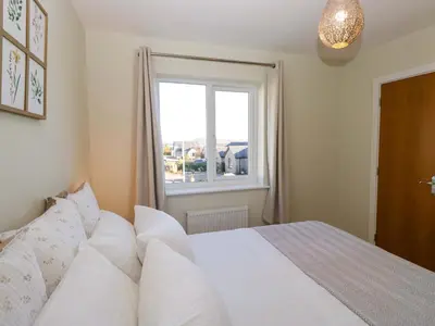 a bedroom with a white bed and a window at Oversands View in Grange Over Sands