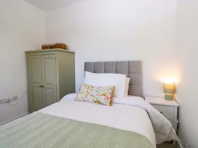 a bedroom with a white bed with a green cabinet at Oversands View in Grange Over Sands