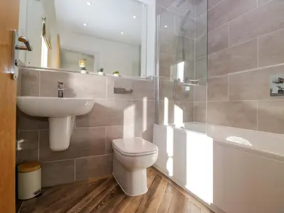 a bathroom with a sink and a toilet and a mirror at Oversands View in Grange Over Sands