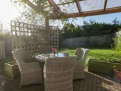 a patio with a table and chairs and a pergola at Oversands View in Grange Over Sands