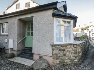 a house with a green door and a window at Drapers Cottage in Grange Over Sands