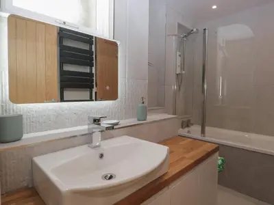 a white bathroom with a sink and a shower at Drapers Cottage in Grange Over Sands