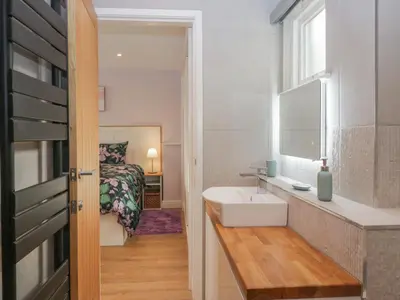 a bathroom with a sink and a bed in a room at Drapers Cottage in Grange Over Sands